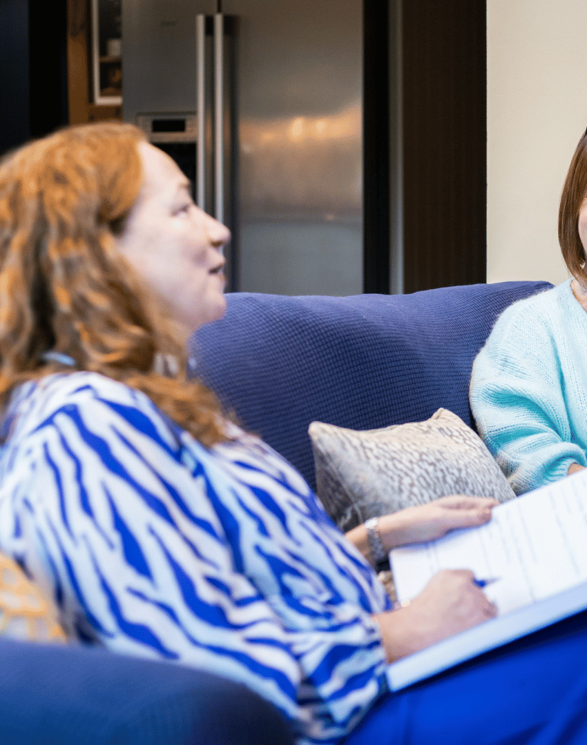 Maxine, founder of Max Purpose Psychology, engaged in a coaching or supervision session with a client, discussing notes in a comfortable, informal setting.